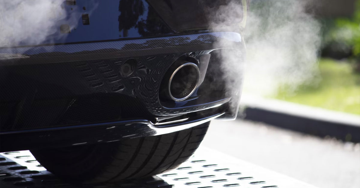 An image of a car idling with the exhaust and exhaust gases in full view