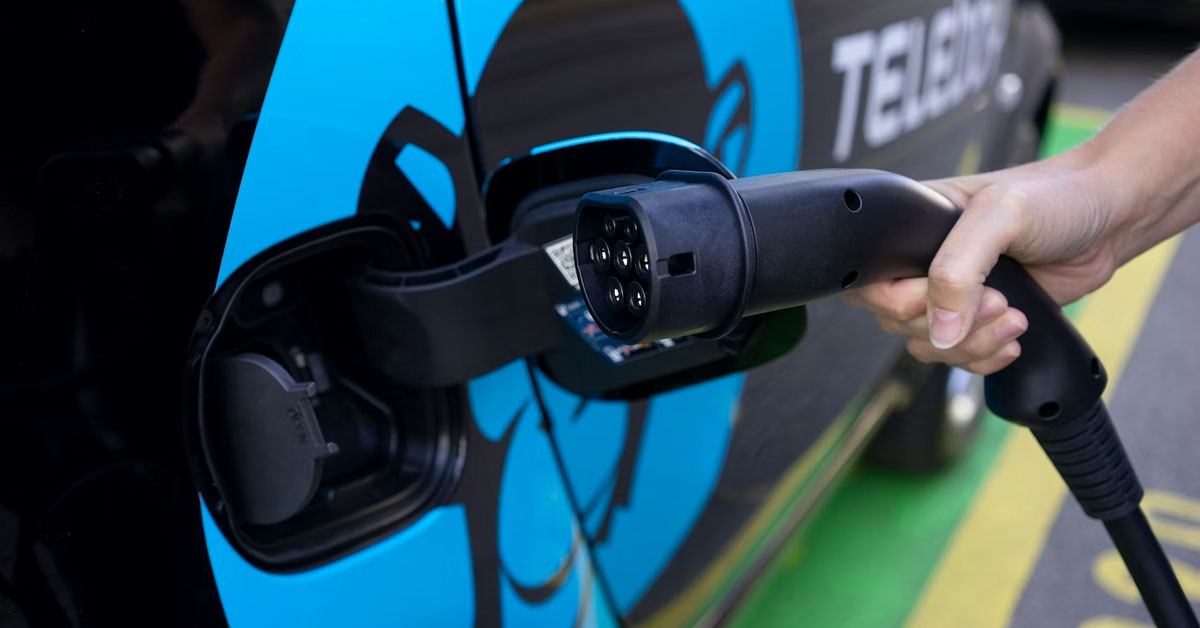 An image of an electric car about to be charged via an electric charging plug